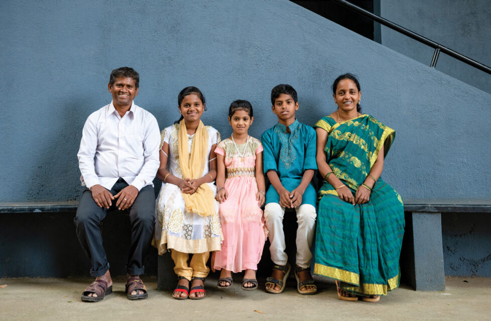 Indian family smiling together sitting on bench