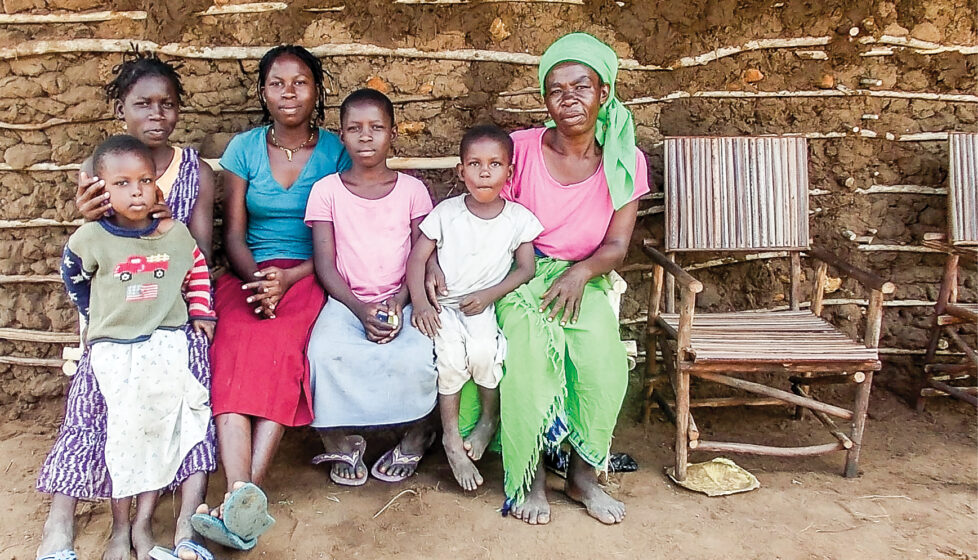 A woman and children sitting in front of their house